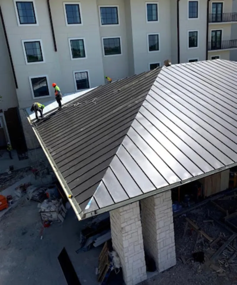Crew installing standing seam metal roof panels on a commercial project in Allen Park